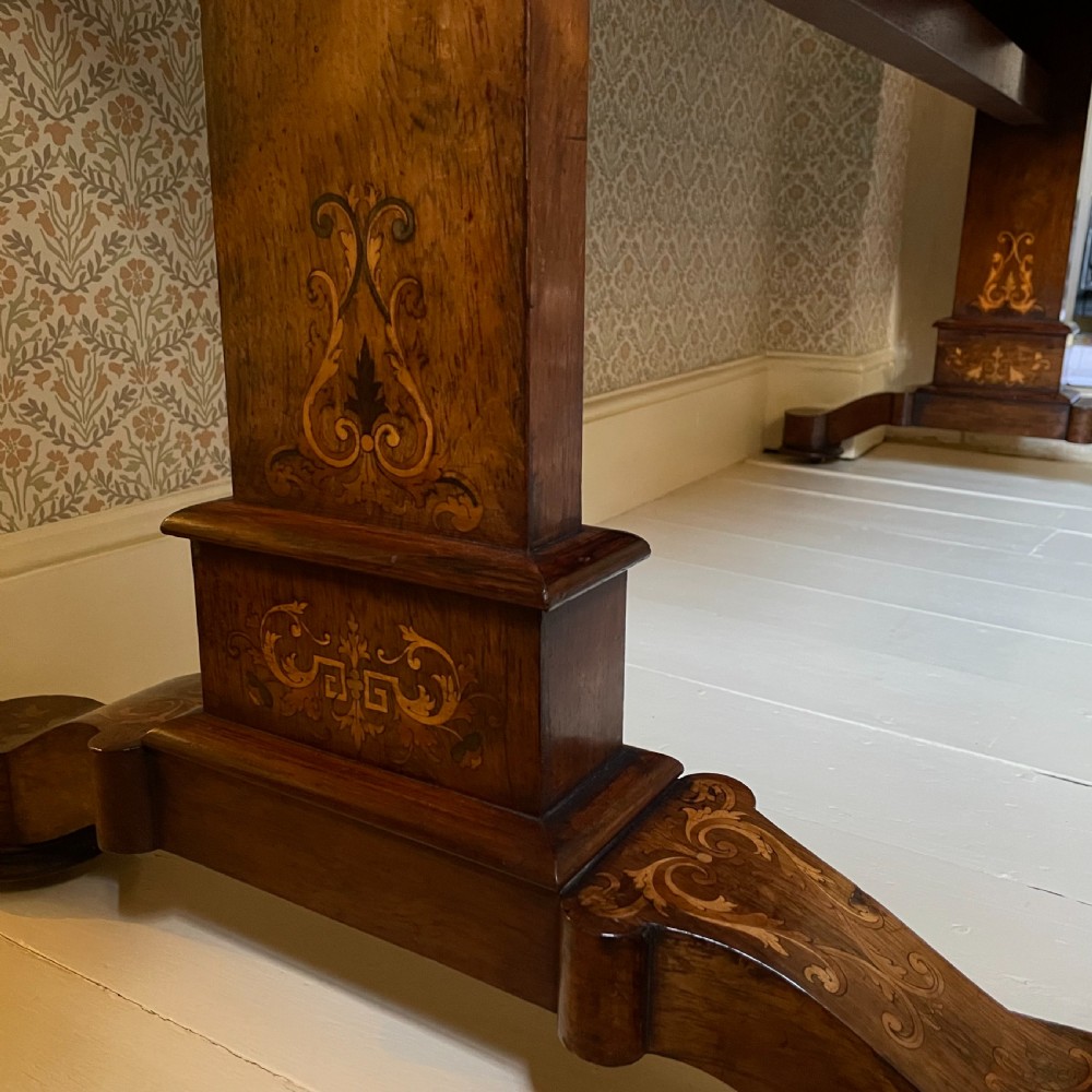 A Late Regency rectangular rosewood library table featuring inlaid floral marquetry along the frieze and pedestal supports. View VI