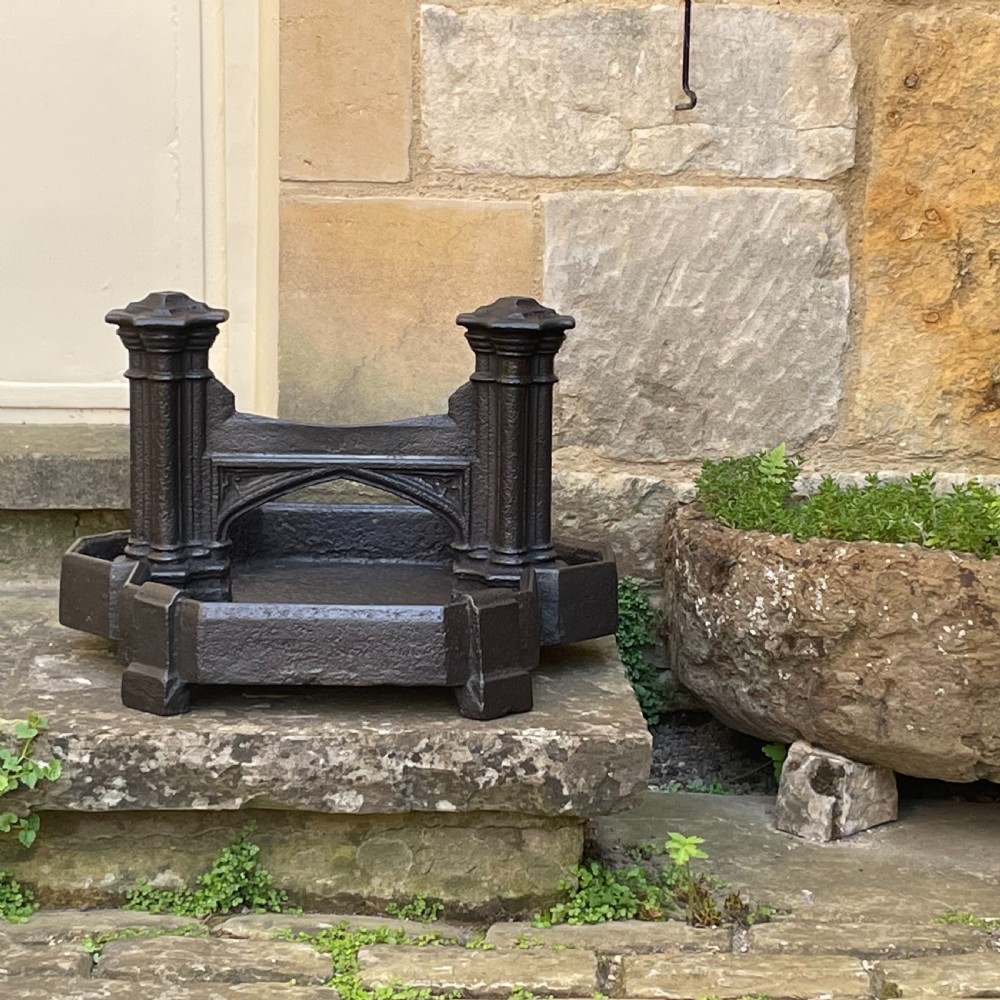 A heavy Victorian cast iron boot scraper featuring Gothic revival pointed arches, twin clustered columns, and an integrated tray base.