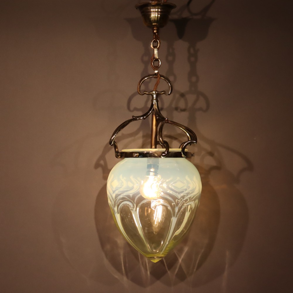 An Arts and Crafts brass pendant light featuring a hanging chain, curved brass frame, and a bulbous opalescent glass shade with molded relief patterns. View III