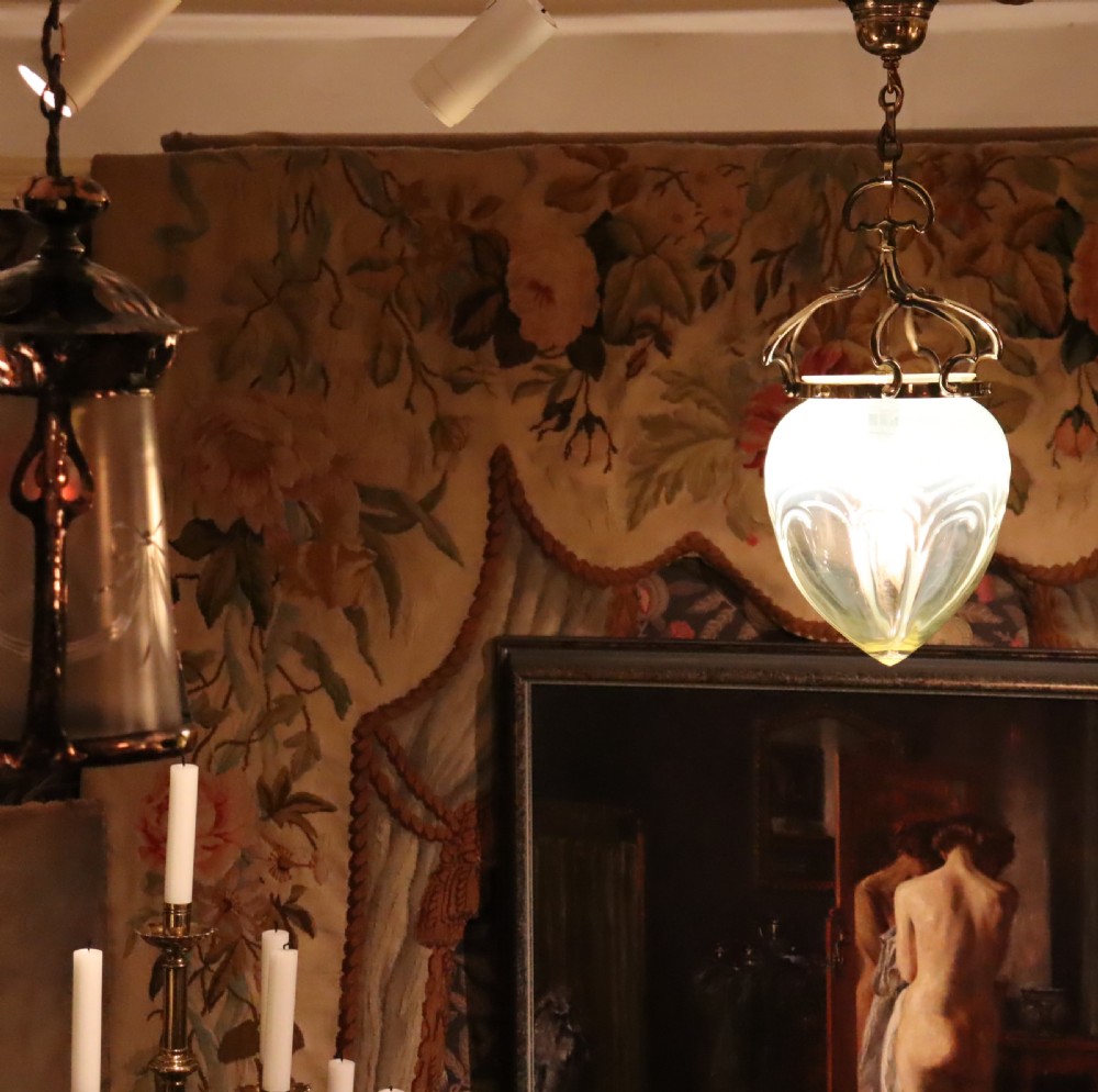An Arts and Crafts brass pendant light featuring a hanging chain, curved brass frame, and a bulbous opalescent glass shade with molded relief patterns. View IV