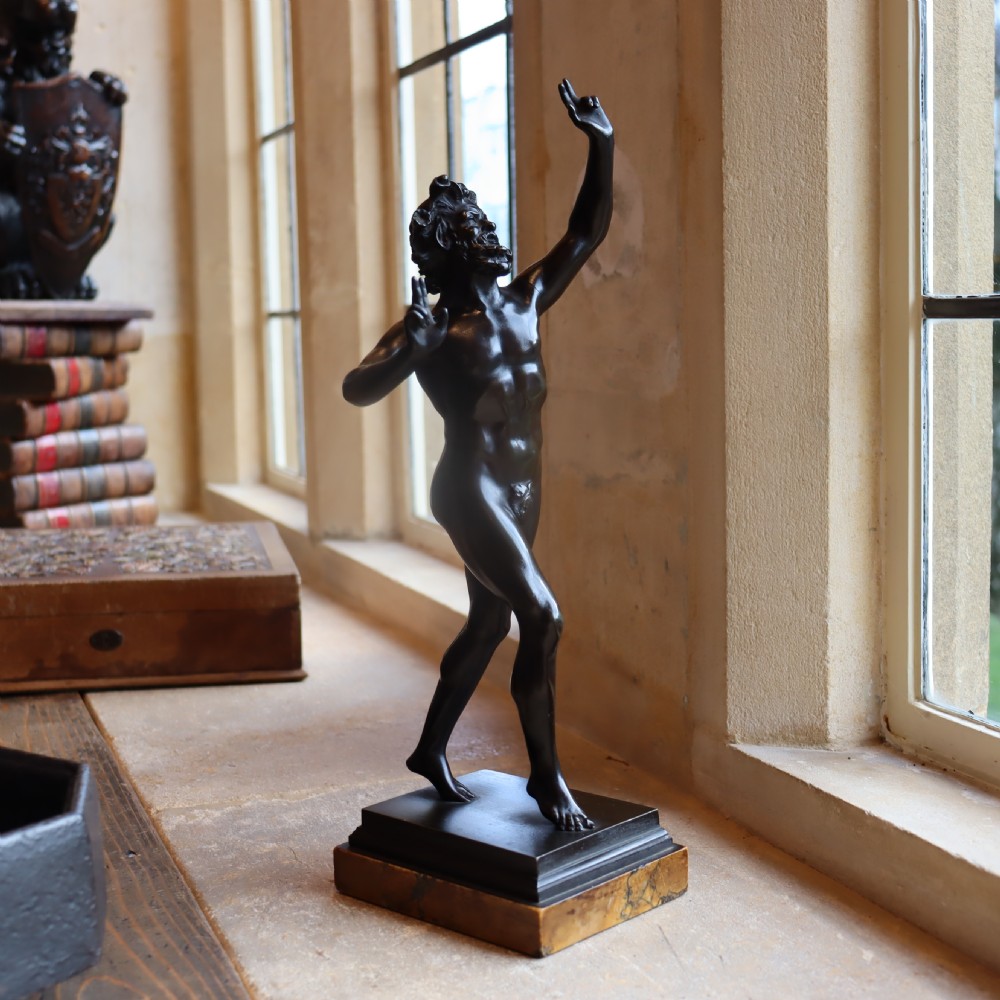 A dark patinated bronze figure depicting the Dancing Faun of Pompeii mounted on a moulded bronze and marble plinth base. View II