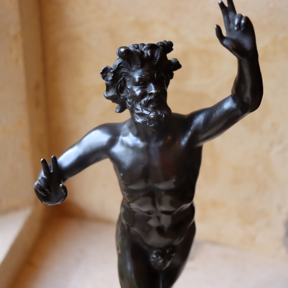 A dark patinated bronze figure depicting the Dancing Faun of Pompeii mounted on a moulded bronze and marble plinth base. View III