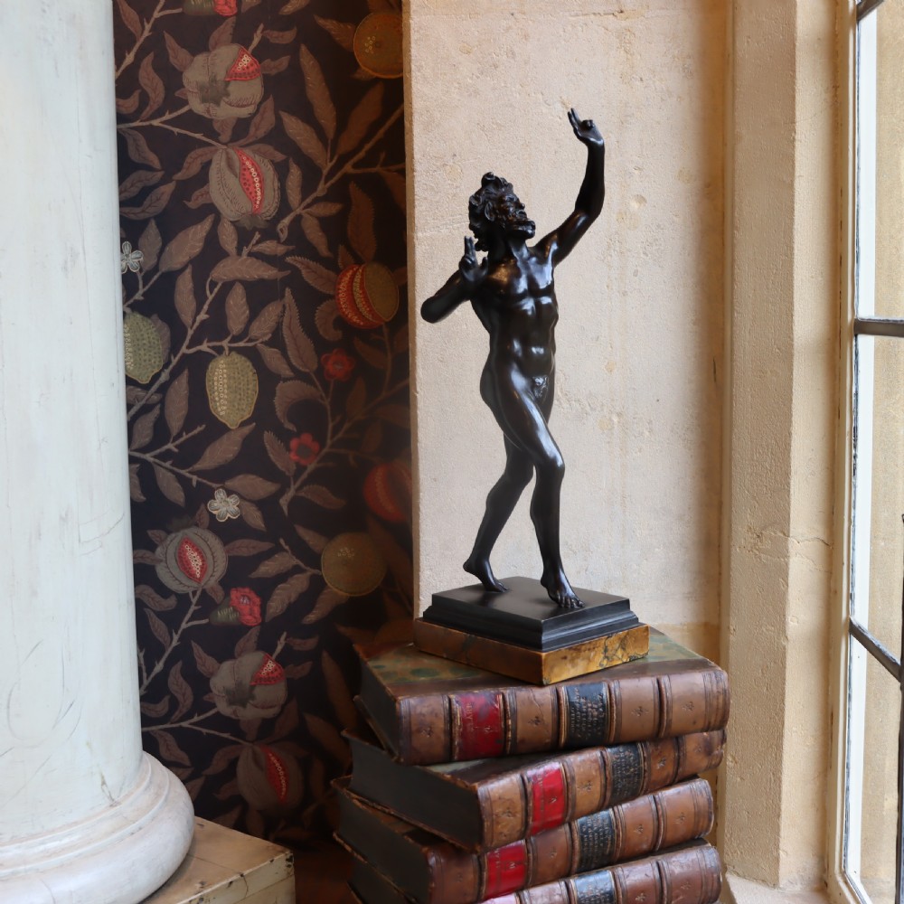 A dark patinated bronze figure depicting the Dancing Faun of Pompeii mounted on a moulded bronze and marble plinth base. View IV