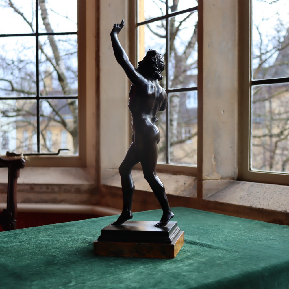 A dark patinated bronze figure depicting the Dancing Faun of Pompeii mounted on a moulded bronze and marble plinth base. View V