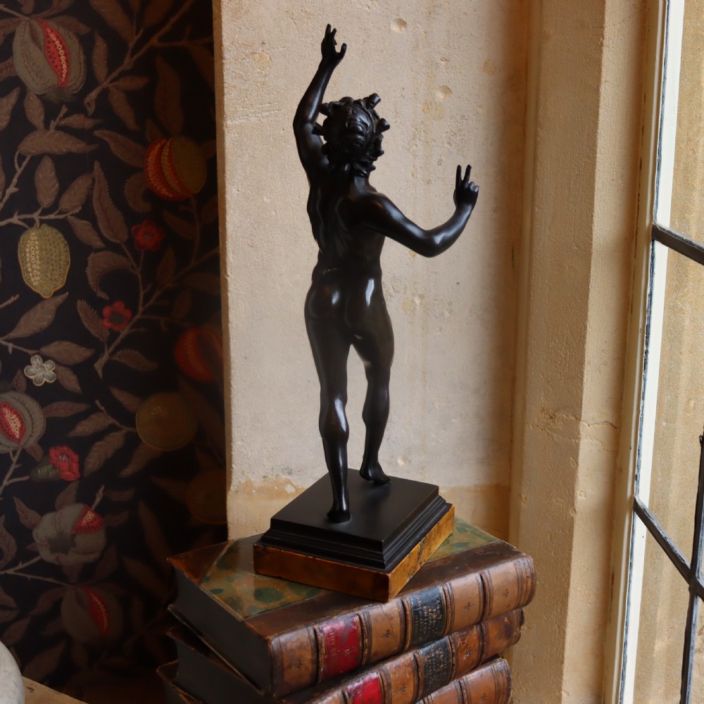 A dark patinated bronze figure depicting the Dancing Faun of Pompeii mounted on a moulded bronze and marble plinth base. View VI