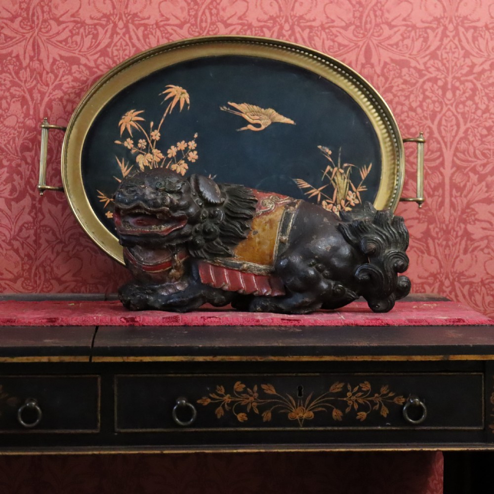 A hand-carved wooden Chinese foo dog sculpture featuring polychrome painted details in red, yellow, and dark green. View III