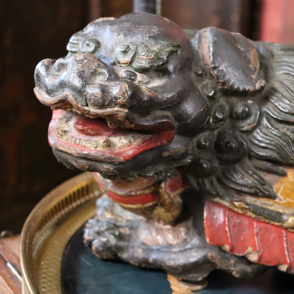 A hand-carved wooden Chinese foo dog sculpture featuring polychrome painted details in red, yellow, and dark green. View IV
