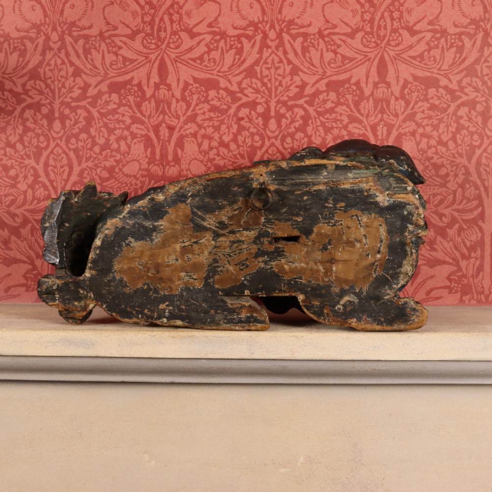 A hand-carved wooden Chinese foo dog sculpture featuring polychrome painted details in red, yellow, and dark green. View V