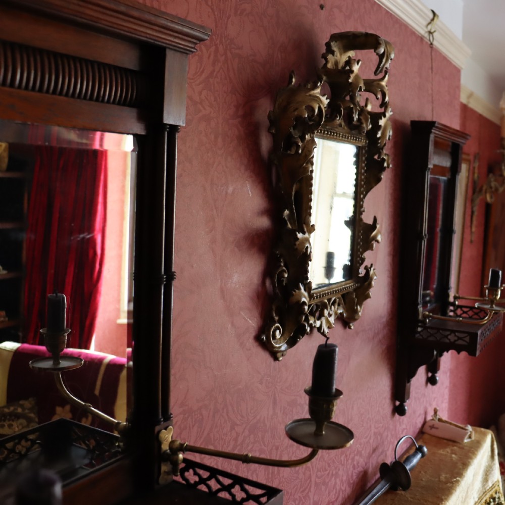 An antique Florentine wall mirror featuring a carved giltwood frame decorated with scrolling acanthus leaves and a beaded inner border surrounding an aged glass plate. View II
