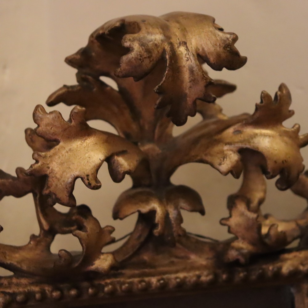 An antique Florentine wall mirror featuring a carved giltwood frame decorated with scrolling acanthus leaves and a beaded inner border surrounding an aged glass plate. View III