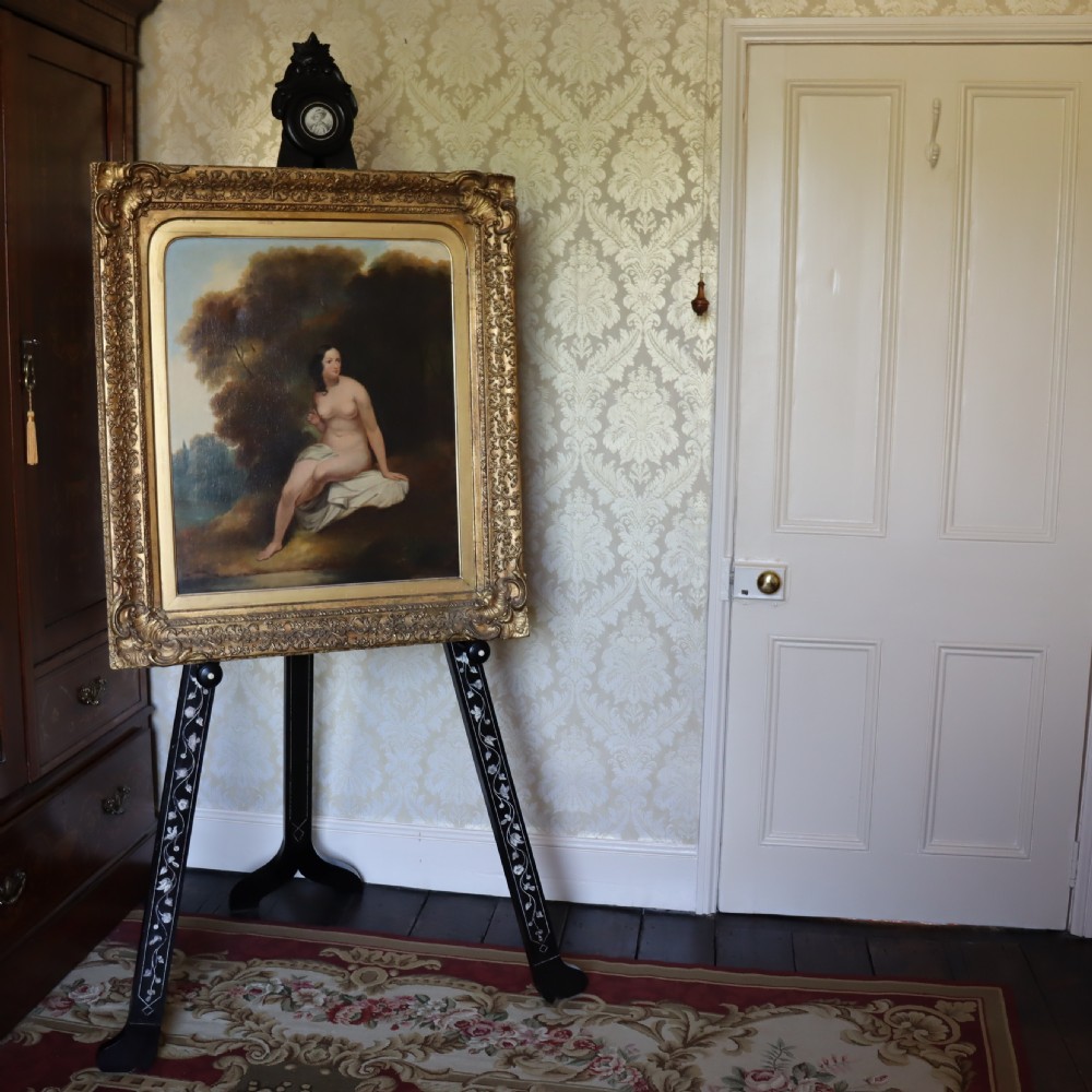 A tall black ebonised gallery easel decorated with white floral inlay along the legs and a carved medallion at the top crest. View II