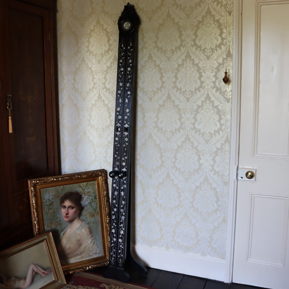 A tall black ebonised gallery easel decorated with white floral inlay along the legs and a carved medallion at the top crest. View IV