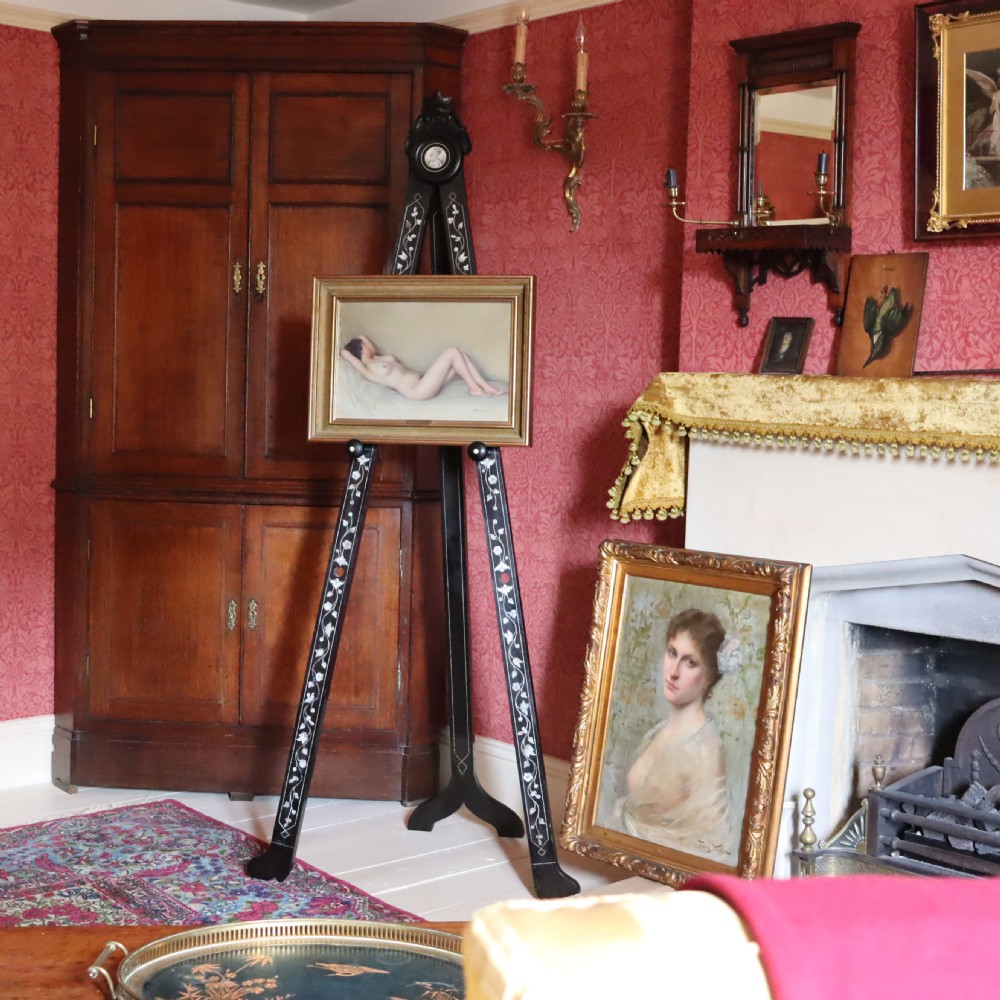 A tall black ebonised gallery easel decorated with white floral inlay along the legs and a carved medallion at the top crest. View VIII