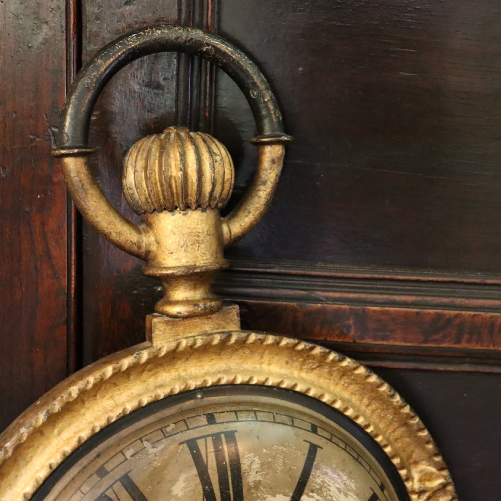 A late 19th-century oversized pocket watch trade sign with a gilded frame, Roman numerals on the dial, and embossed text reading Watches, Jewellery, Clocks. View IV
