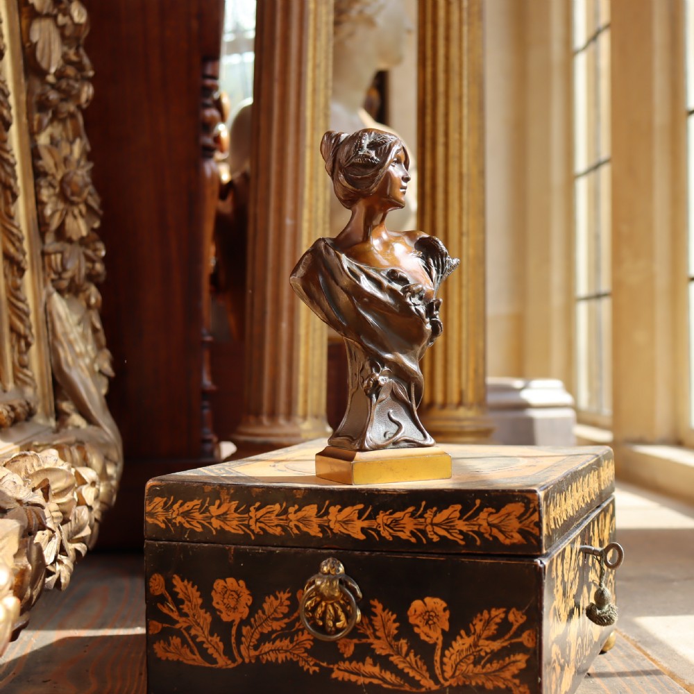An Art Nouveau patinated bronze bust depicting a young woman adorned with ears of wheat and flowing drapery, set on a gilt base. View IV