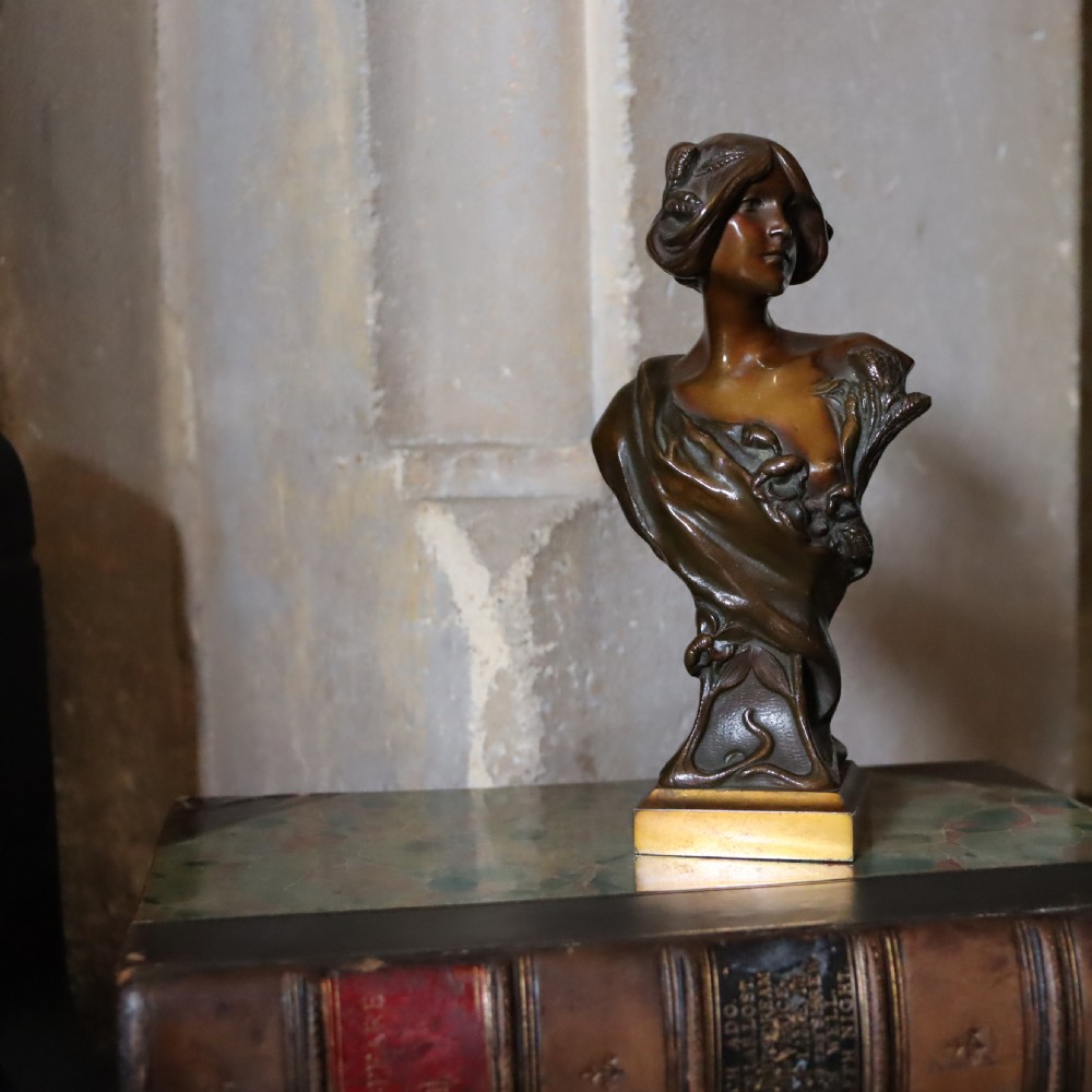 An Art Nouveau patinated bronze bust depicting a young woman adorned with ears of wheat and flowing drapery, set on a gilt base. View II