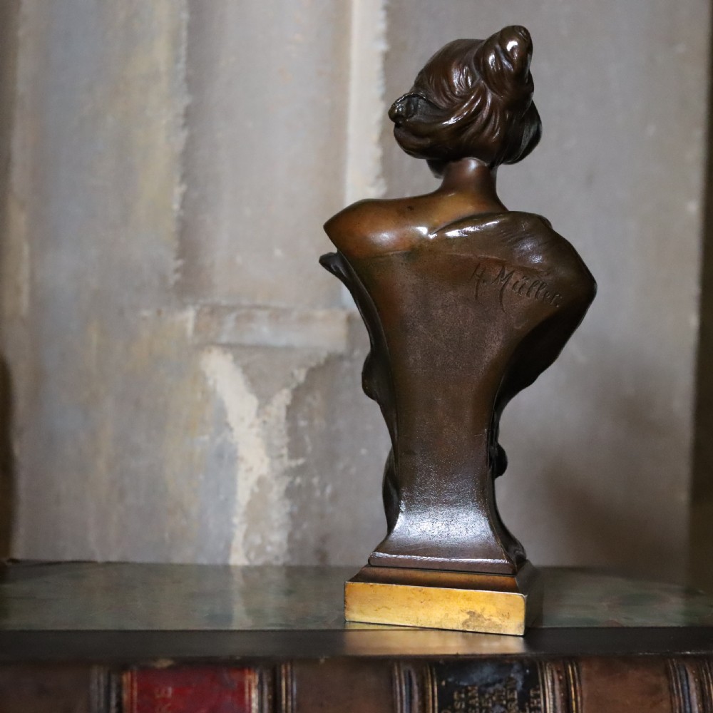 An Art Nouveau patinated bronze bust depicting a young woman adorned with ears of wheat and flowing drapery, set on a gilt base. View III