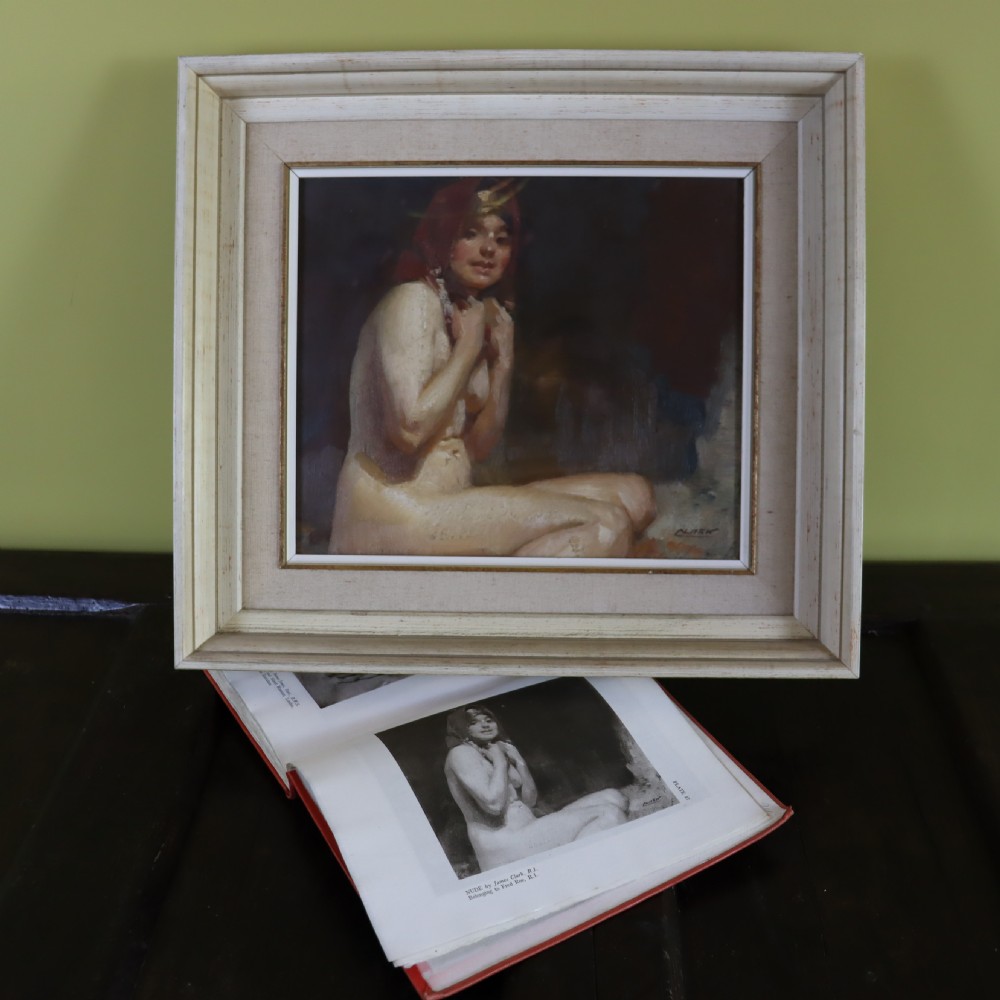 A framed antique oil painting depicting a seated female nude with a red head covering, presented in a light cream moulded wooden frame. View II