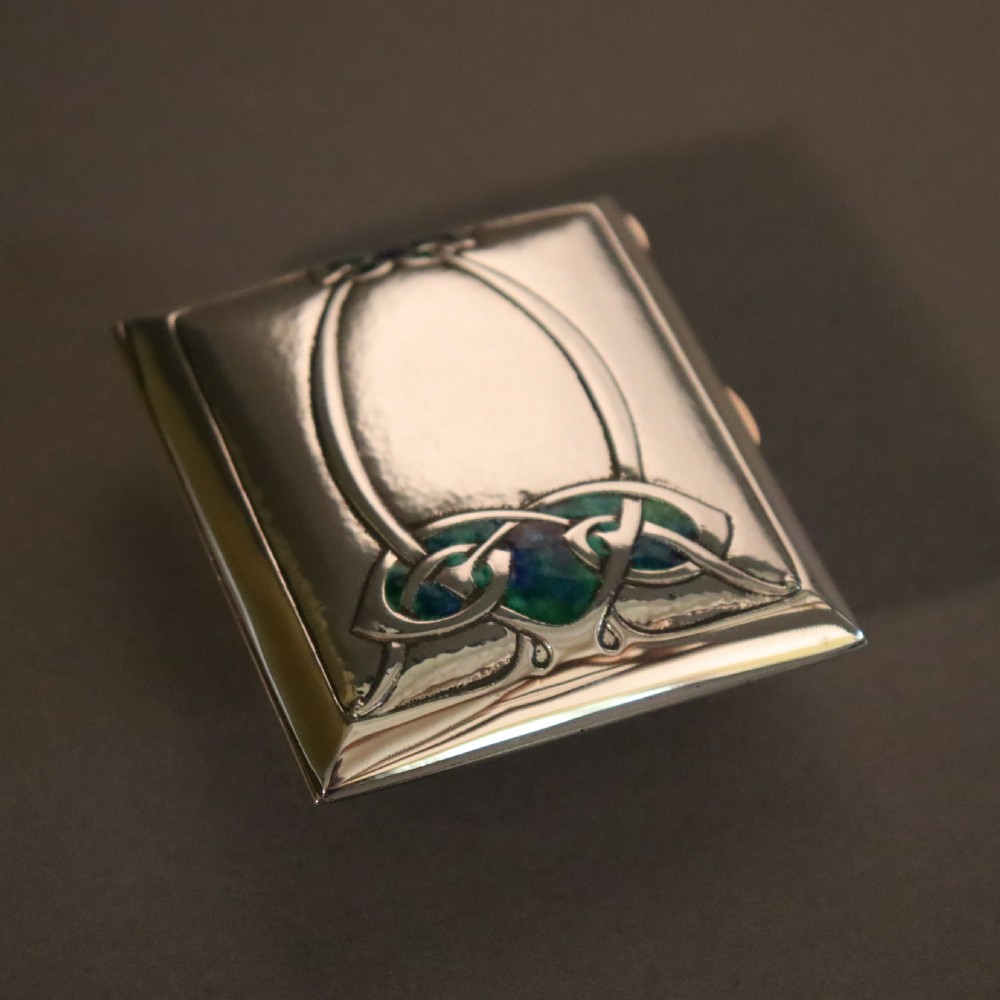 A rectangular planished sterling silver case featuring a raised Celtic knotwork motif filled with vibrant blue and green enamel. View III