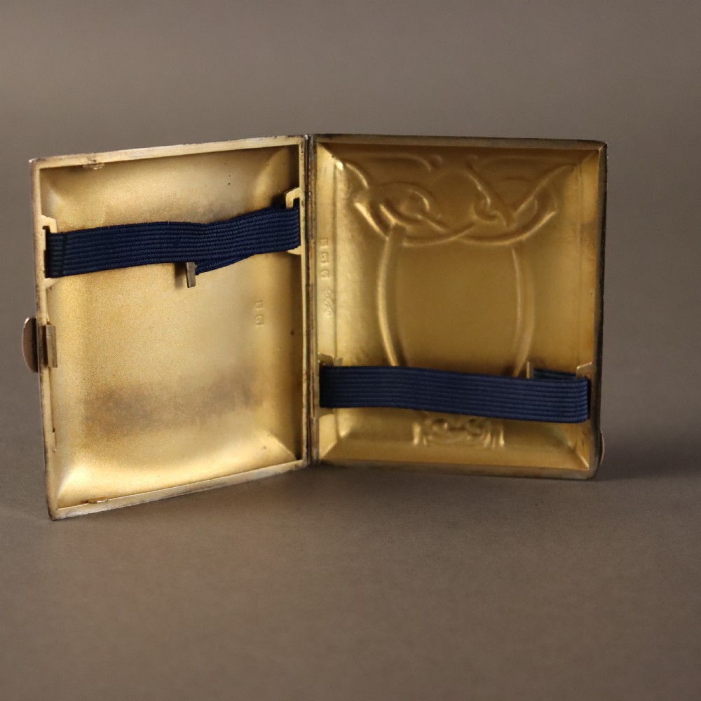 A rectangular planished sterling silver case featuring a raised Celtic knotwork motif filled with vibrant blue and green enamel. View VI