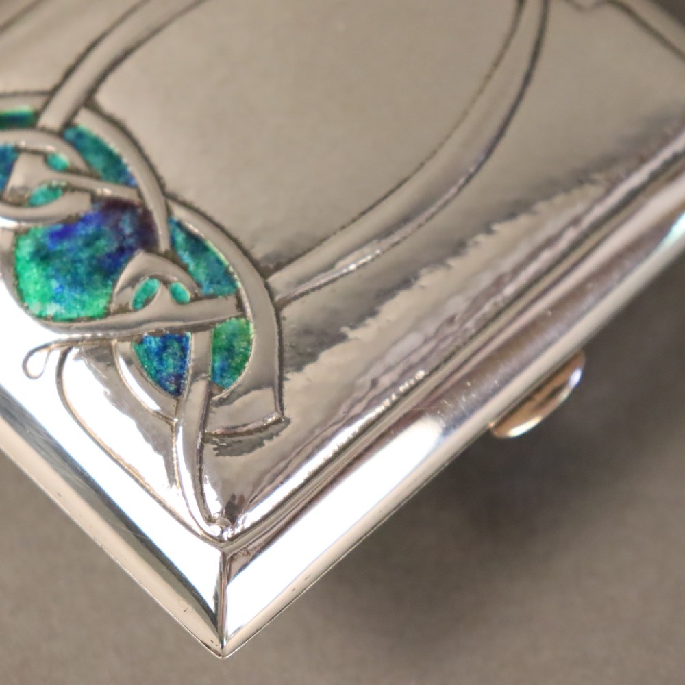 A rectangular planished sterling silver case featuring a raised Celtic knotwork motif filled with vibrant blue and green enamel. View VII