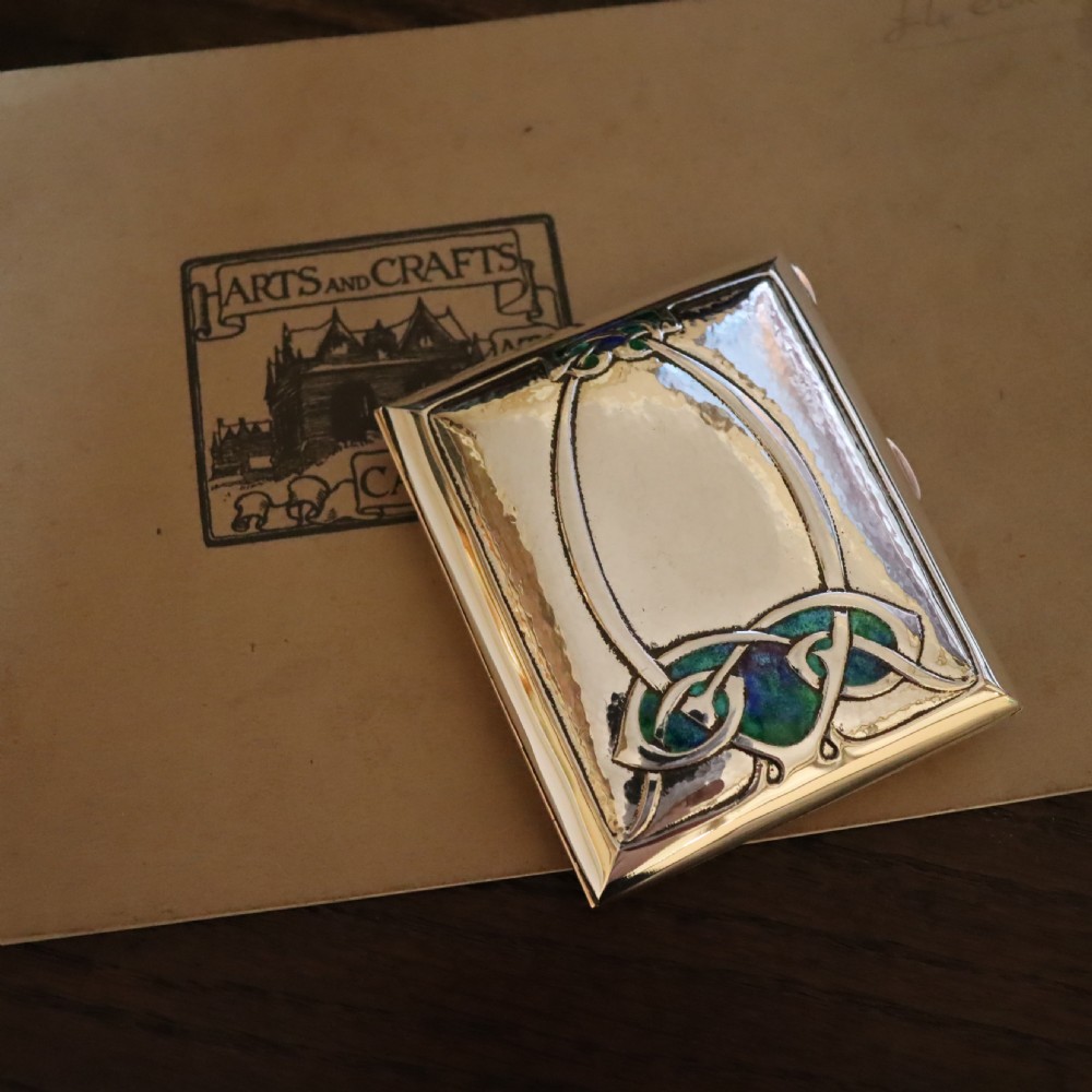 A rectangular planished sterling silver case featuring a raised Celtic knotwork motif filled with vibrant blue and green enamel. View VIII