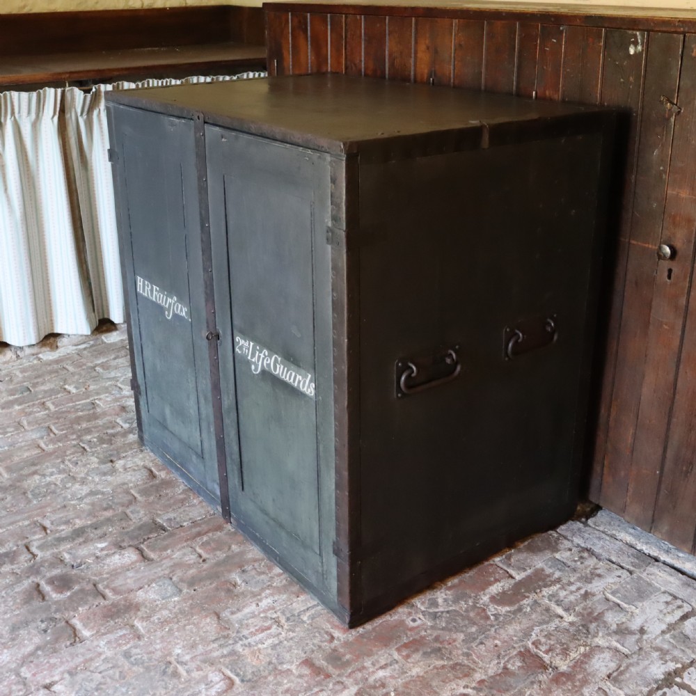 A large dark green metal-bound military campaign travelling case with stencilled lettering on the front panels and iron drop handles on the side. View II