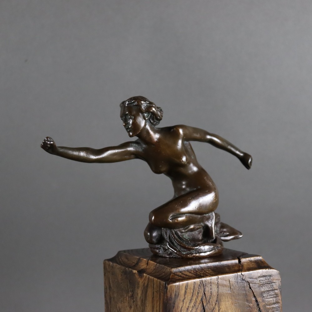 An Art Deco dark bronze sculpture of a kneeling nude woman reaching forward, mounted on a rustic square timber base. View V