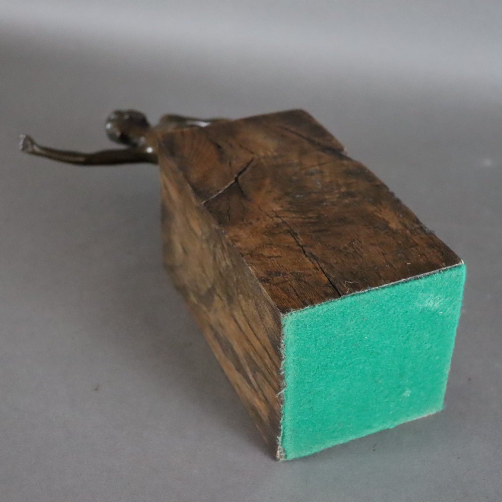 An Art Deco dark bronze sculpture of a kneeling nude woman reaching forward, mounted on a rustic square timber base. View VI