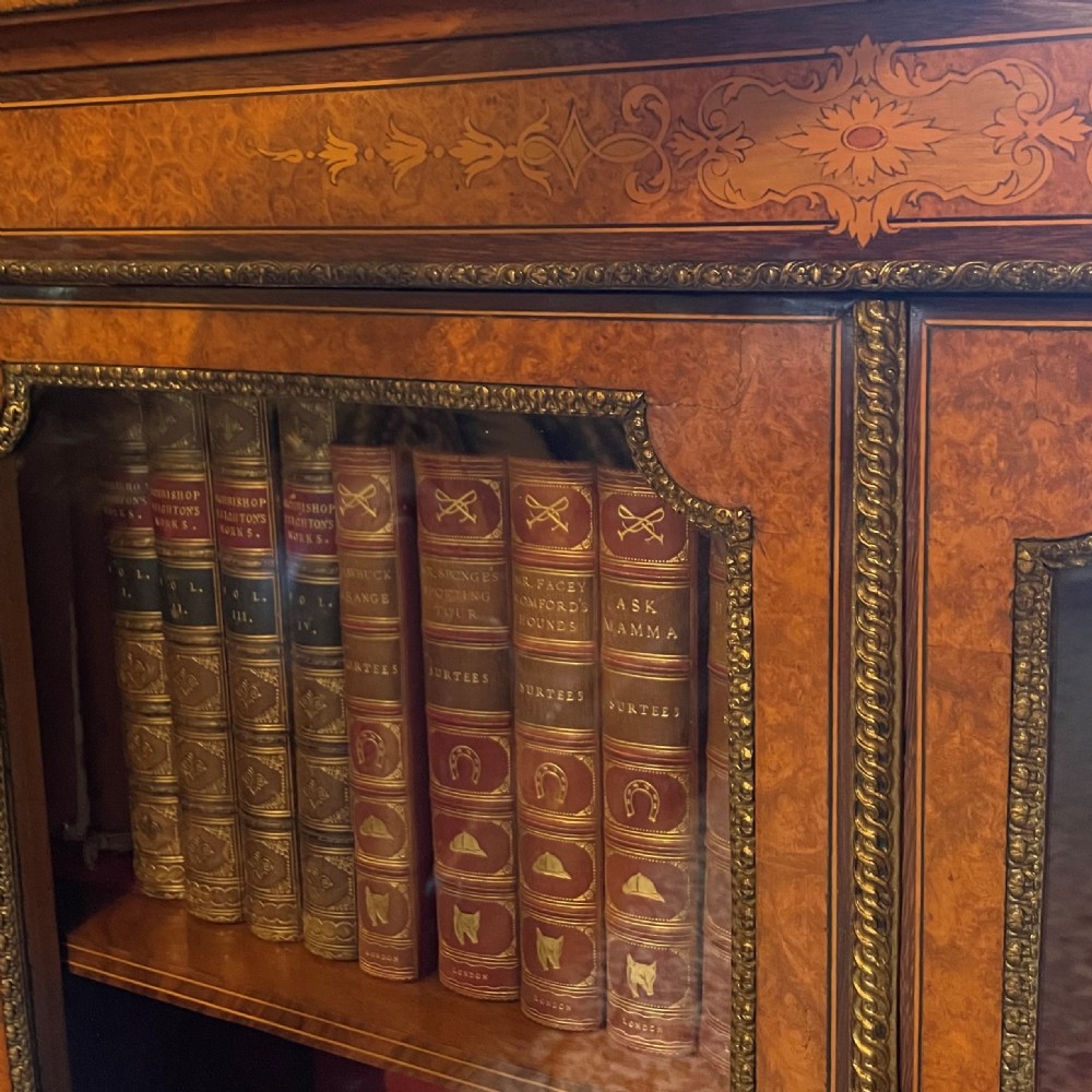 A Victorian burr walnut pier cabinet with two glazed doors, marquetry crossbanding along the frieze, and brass mounts. View III