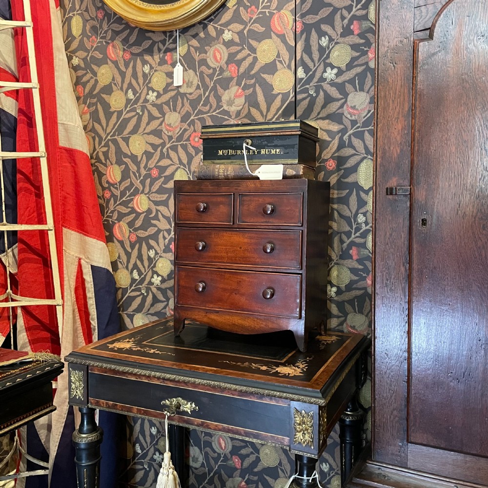 A Georgian mahogany miniature apprentice chest of drawers with turned wooden handles, four graduated drawers, and bracket feet. View II