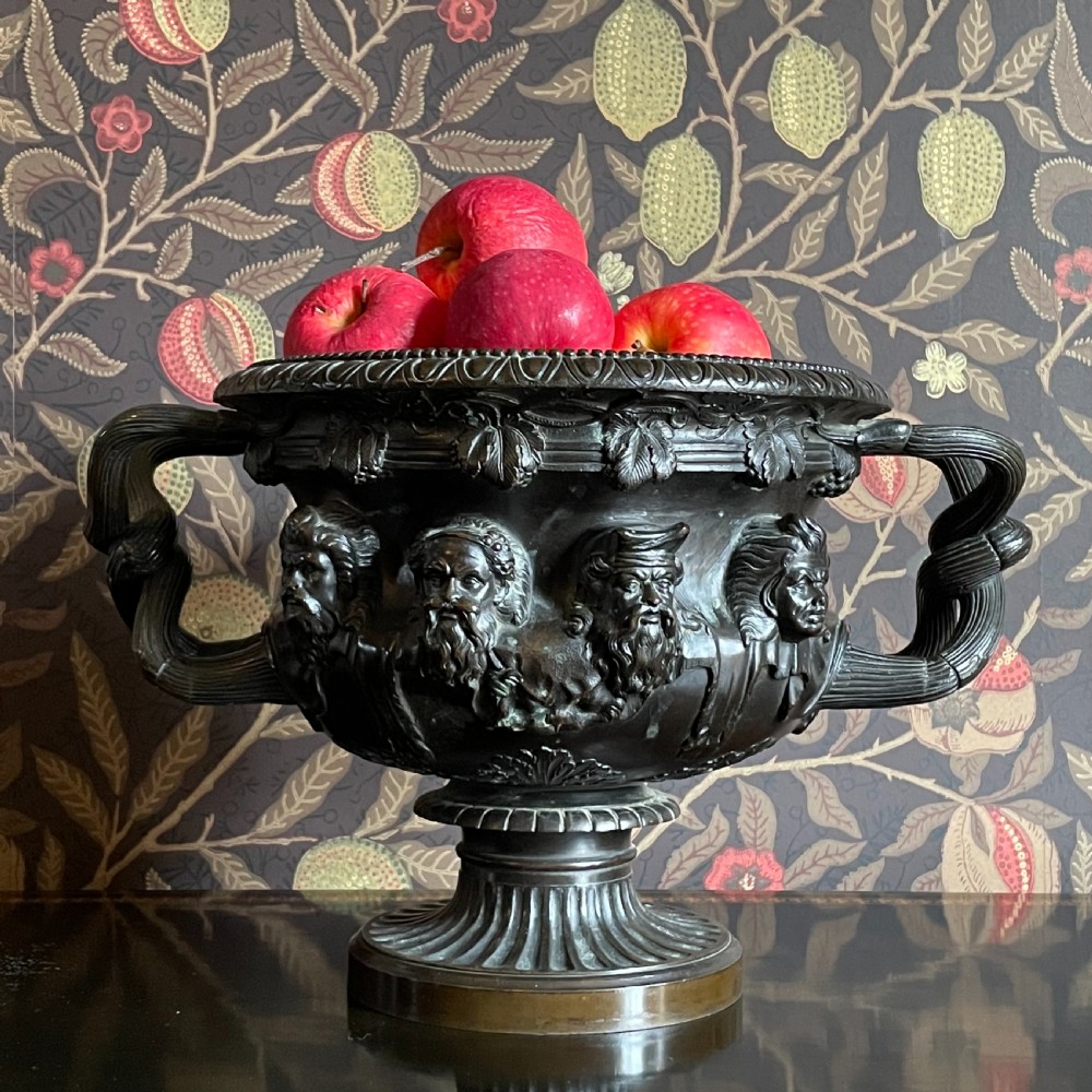 A dark patinated bronze Warwick vase featuring relief Bacchic masks, intertwined vine handles, and a gadrooned pedestal foot. View III