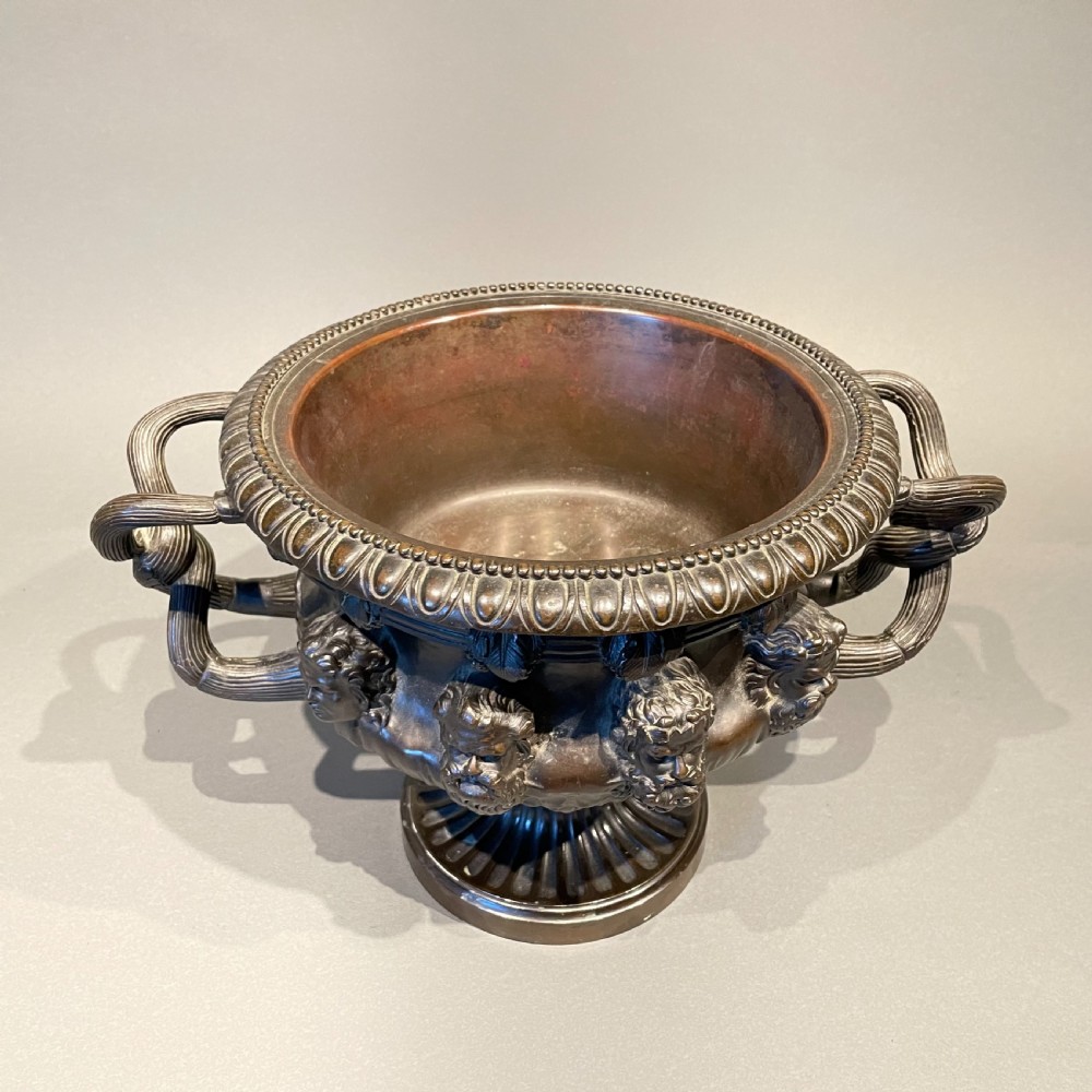 A dark patinated bronze Warwick vase featuring relief Bacchic masks, intertwined vine handles, and a gadrooned pedestal foot. View IV