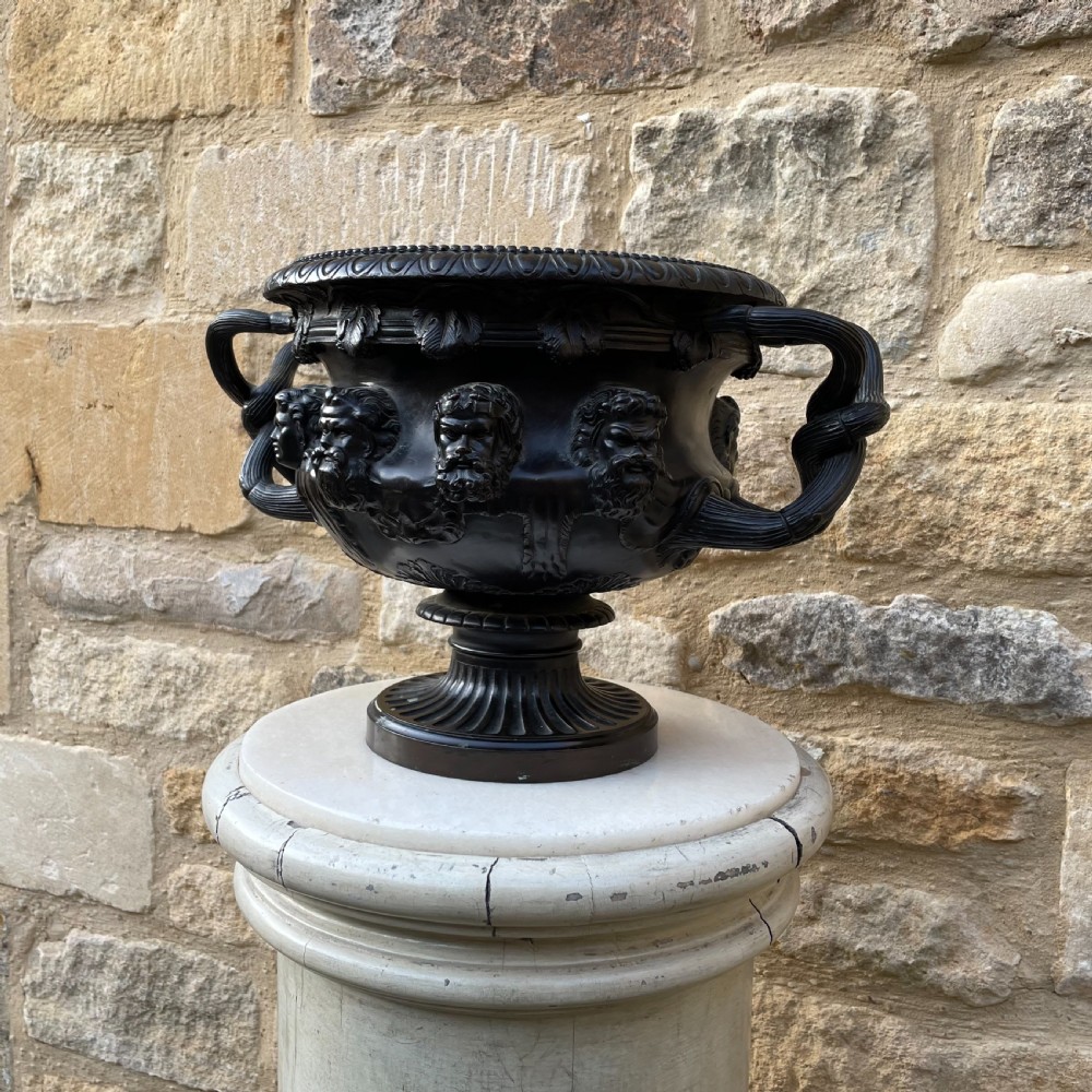 A dark patinated bronze Warwick vase featuring relief Bacchic masks, intertwined vine handles, and a gadrooned pedestal foot. View VI