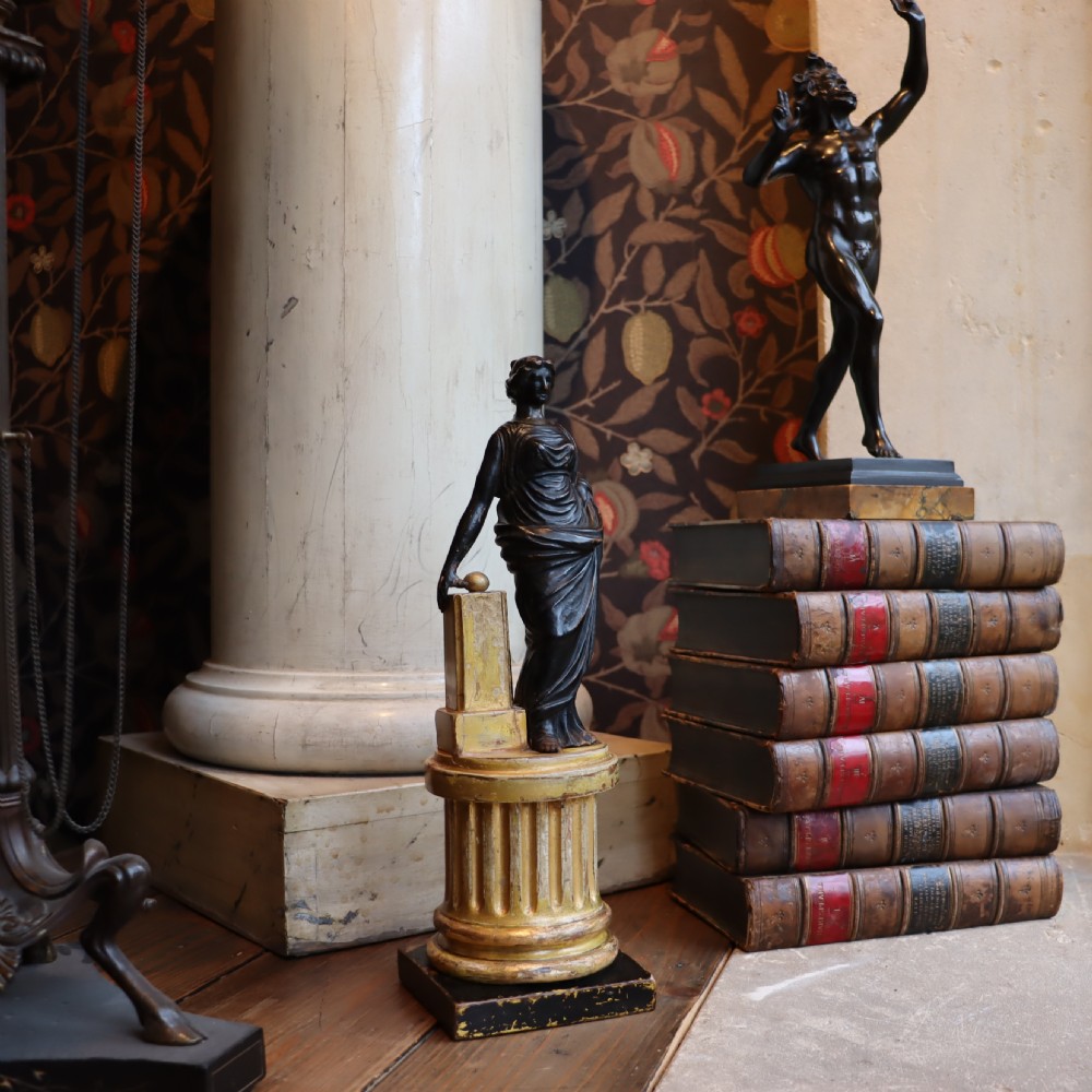 A dark ebonised carved wood figure of the classical goddess Fortuna set atop a gilded fluted column pedestal and square base. View V