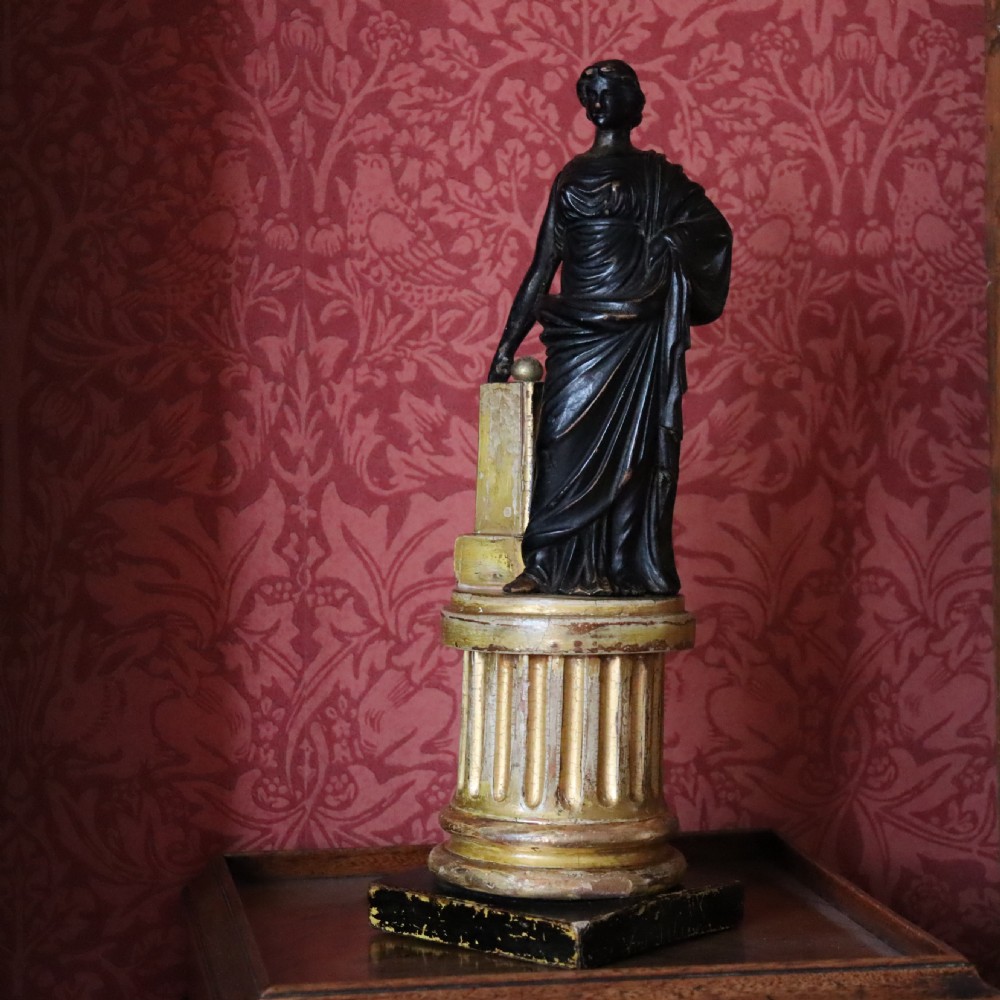 A dark ebonised carved wood figure of the classical goddess Fortuna set atop a gilded fluted column pedestal and square base. View VIII