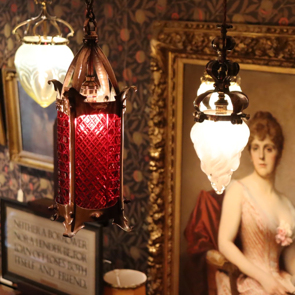 An Arts and Crafts copper hanging lantern fitted with a diamond-moulded cranberry red glass shade. View II