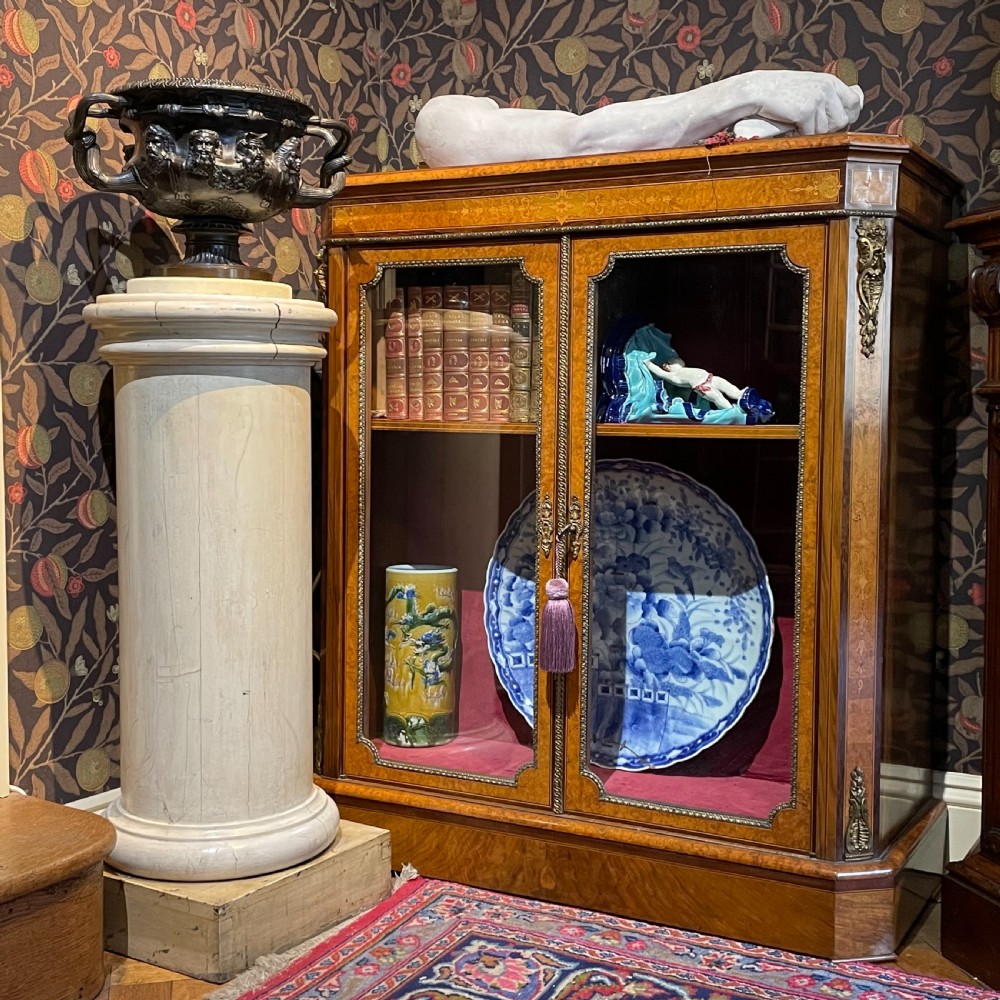 A painted off-white Victorian turned wooden column with a circular molded capital and base resting on a square wooden plinth. View II