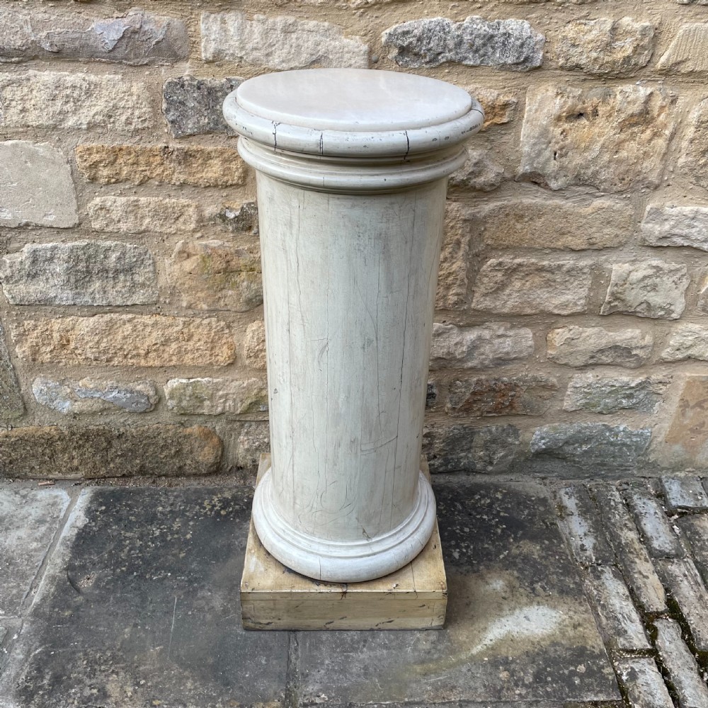 A painted off-white Victorian turned wooden column with a circular molded capital and base resting on a square wooden plinth. View III