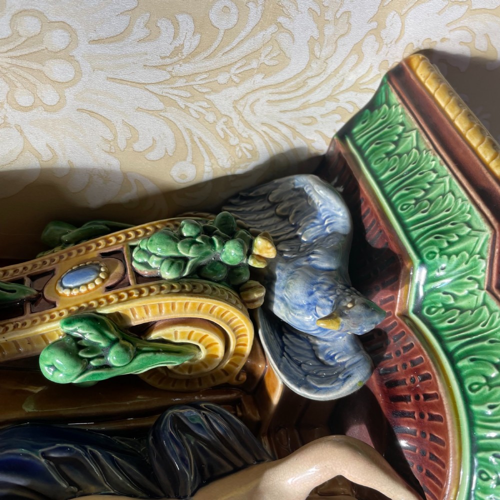 A Victorian Minton majolica wall bracket featuring three sculpted cherubs supporting a green glaze top shelf above a mascaron base. View III