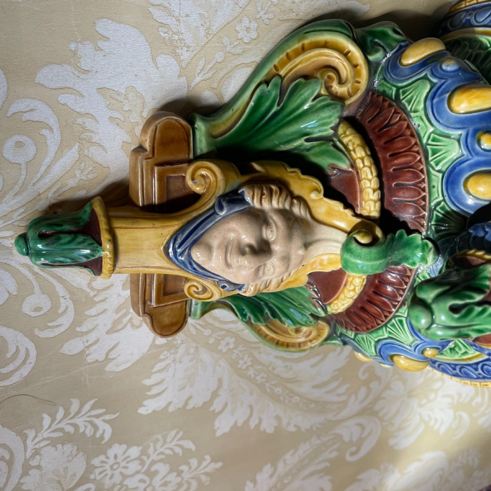 A Victorian Minton majolica wall bracket featuring three sculpted cherubs supporting a green glaze top shelf above a mascaron base. View IV