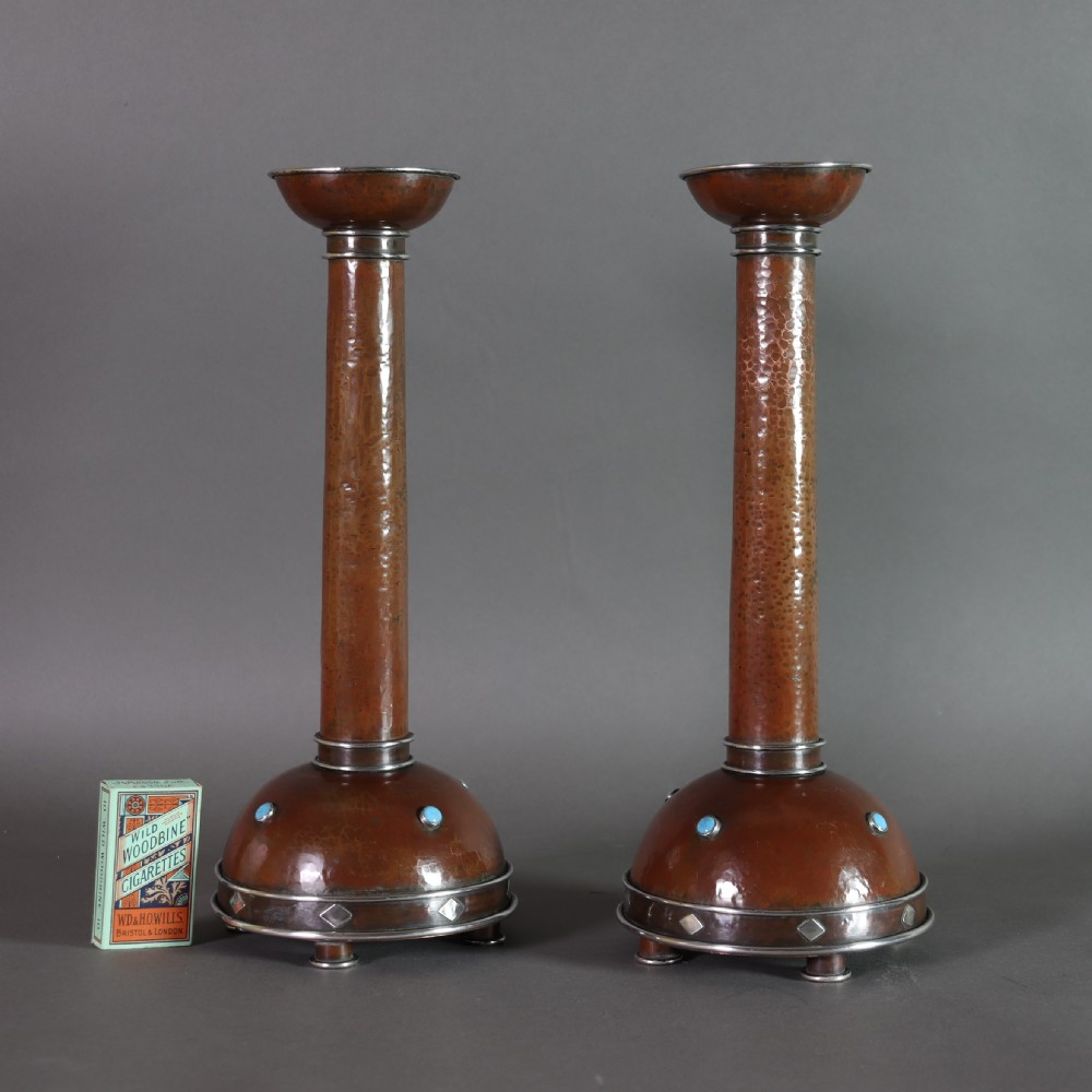 A pair of tall Arts and Crafts hammered copper candlesticks featuring domed bases inlaid with turquoise cabochons and silver detail. View VIII