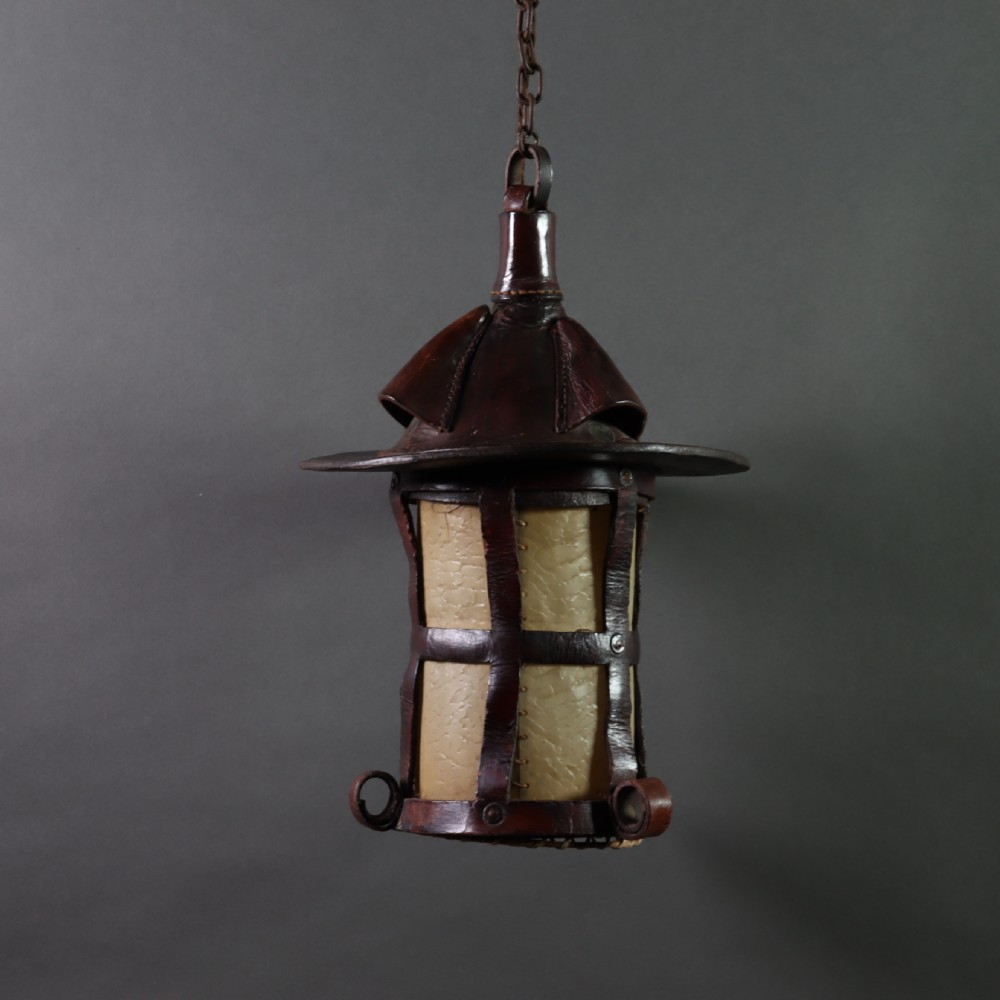 An Arts and Crafts ceiling lantern made of dark chestnut brown hand-stitched leather straps surrounding translucent vellum panels, suspended by a metal chain. View II