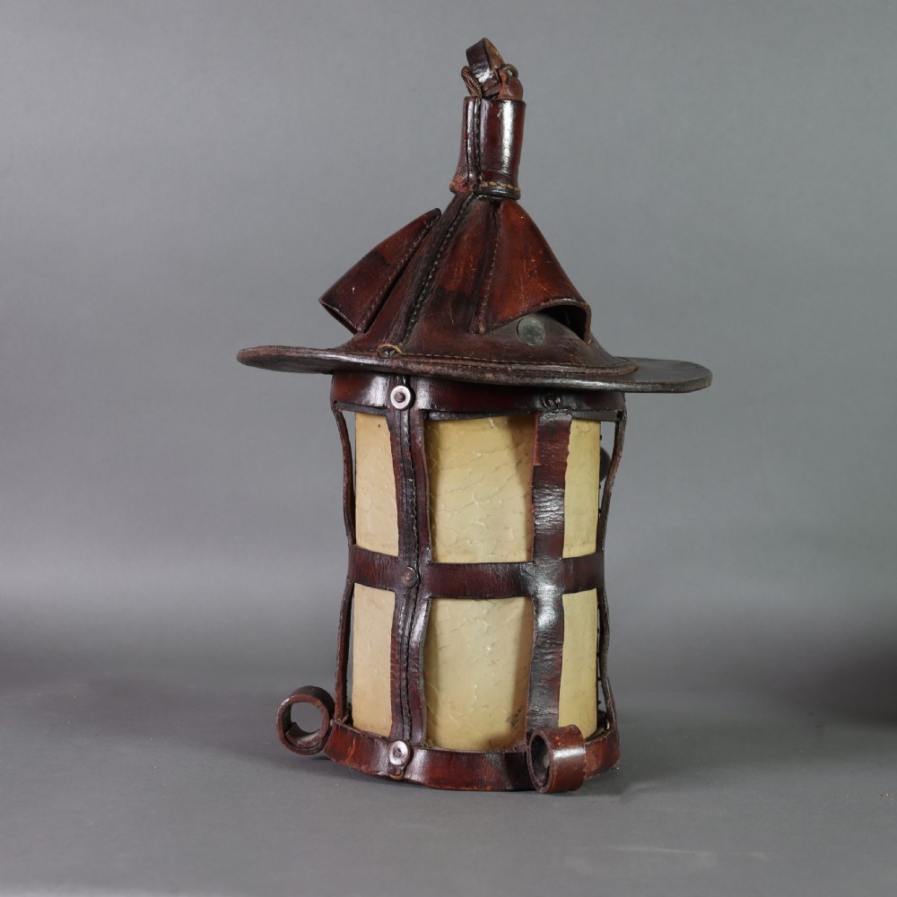 An Arts and Crafts ceiling lantern made of dark chestnut brown hand-stitched leather straps surrounding translucent vellum panels, suspended by a metal chain. View III
