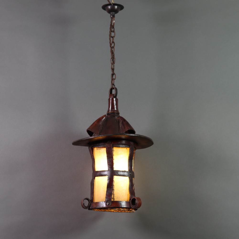 An Arts and Crafts ceiling lantern made of dark chestnut brown hand-stitched leather straps surrounding translucent vellum panels, suspended by a metal chain. View VI