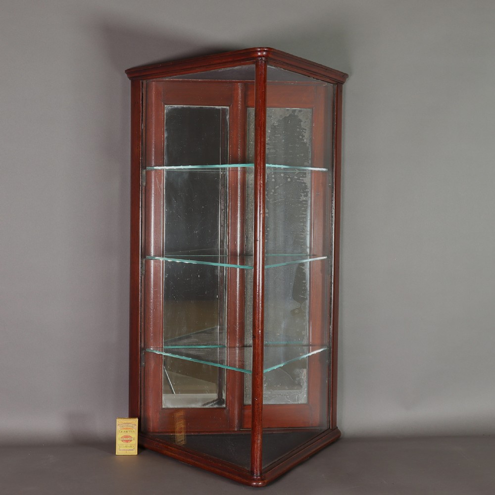 A Victorian mahogany and glass corner display cabinet featuring three glass shelves and mirrored back doors. View IV