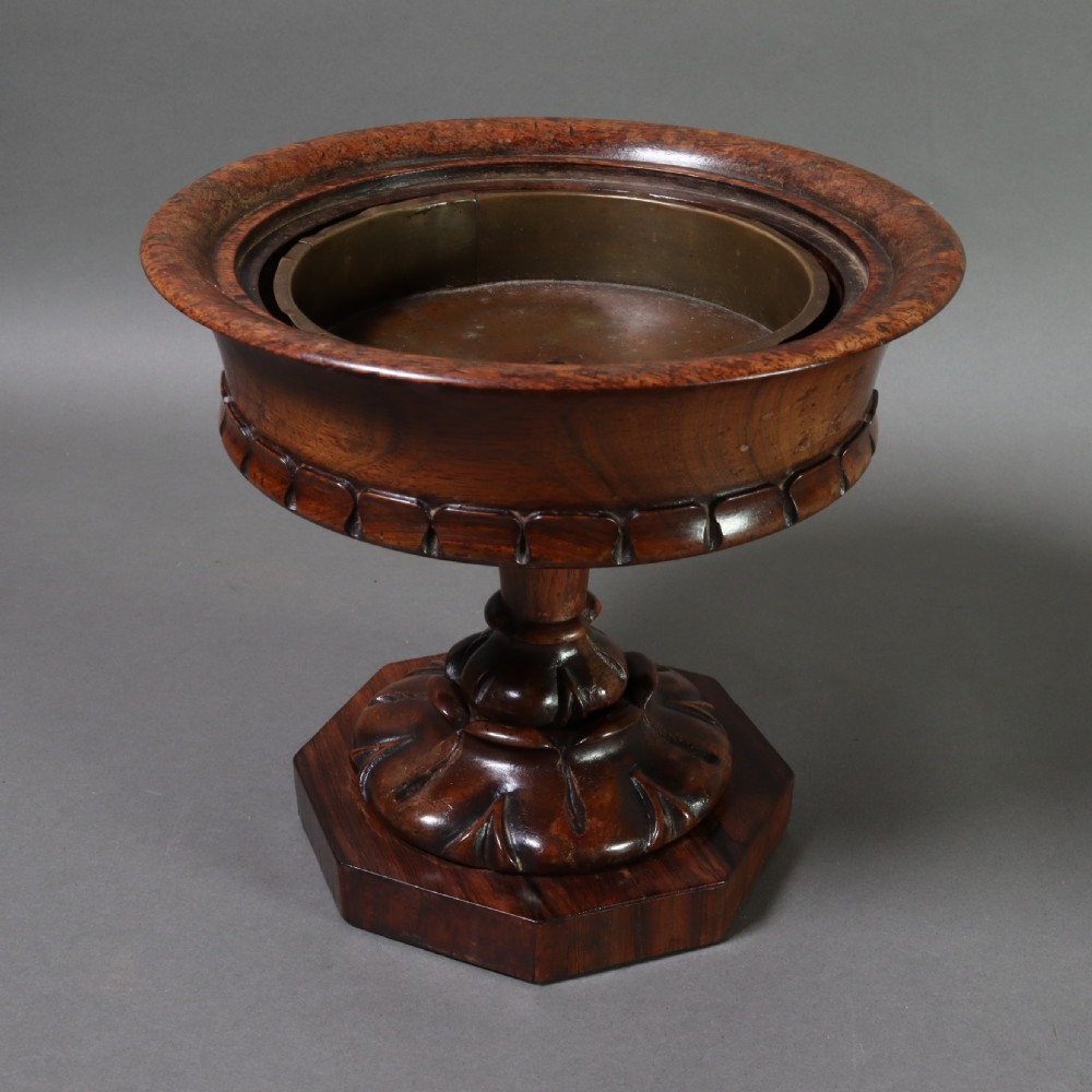 A dark rosewood tazza urn featuring a circular flared rim with an integrated brass liner, supported by a turned pedestal on an octagonal wooden base.