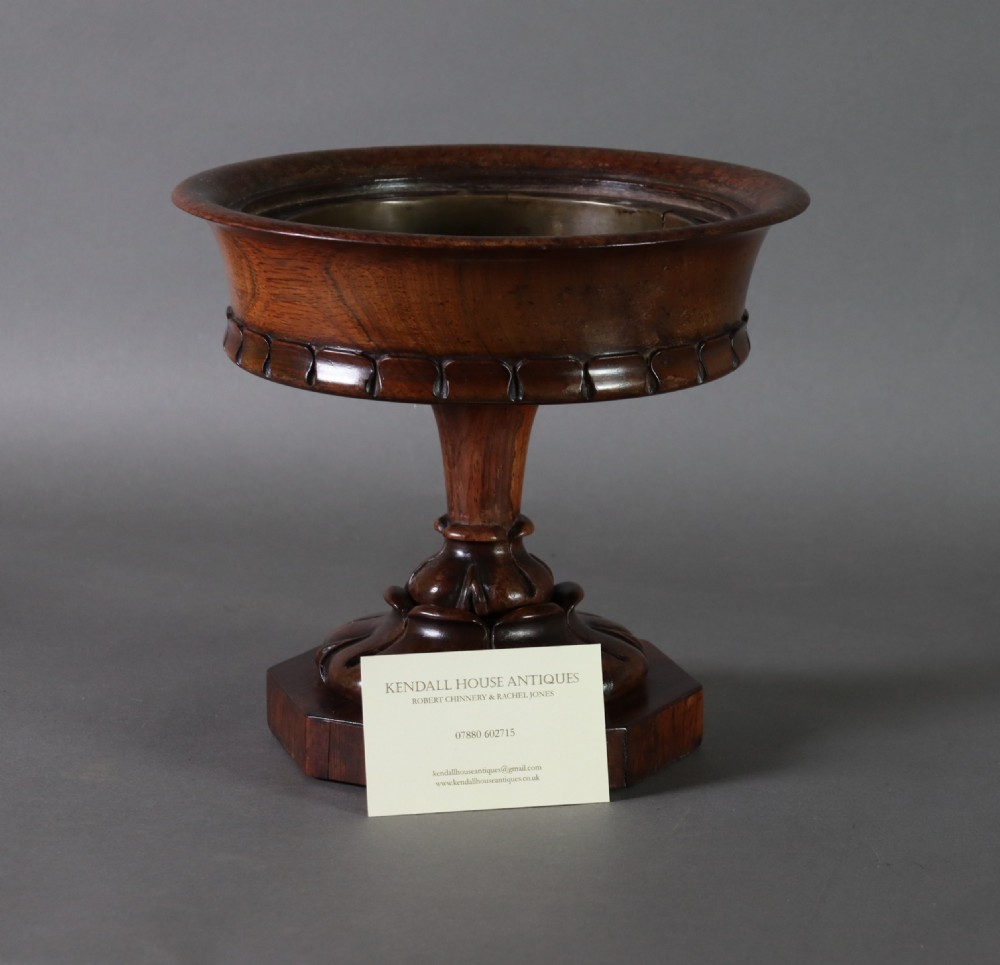 A dark rosewood tazza urn featuring a circular flared rim with an integrated brass liner, supported by a turned pedestal on an octagonal wooden base. View X