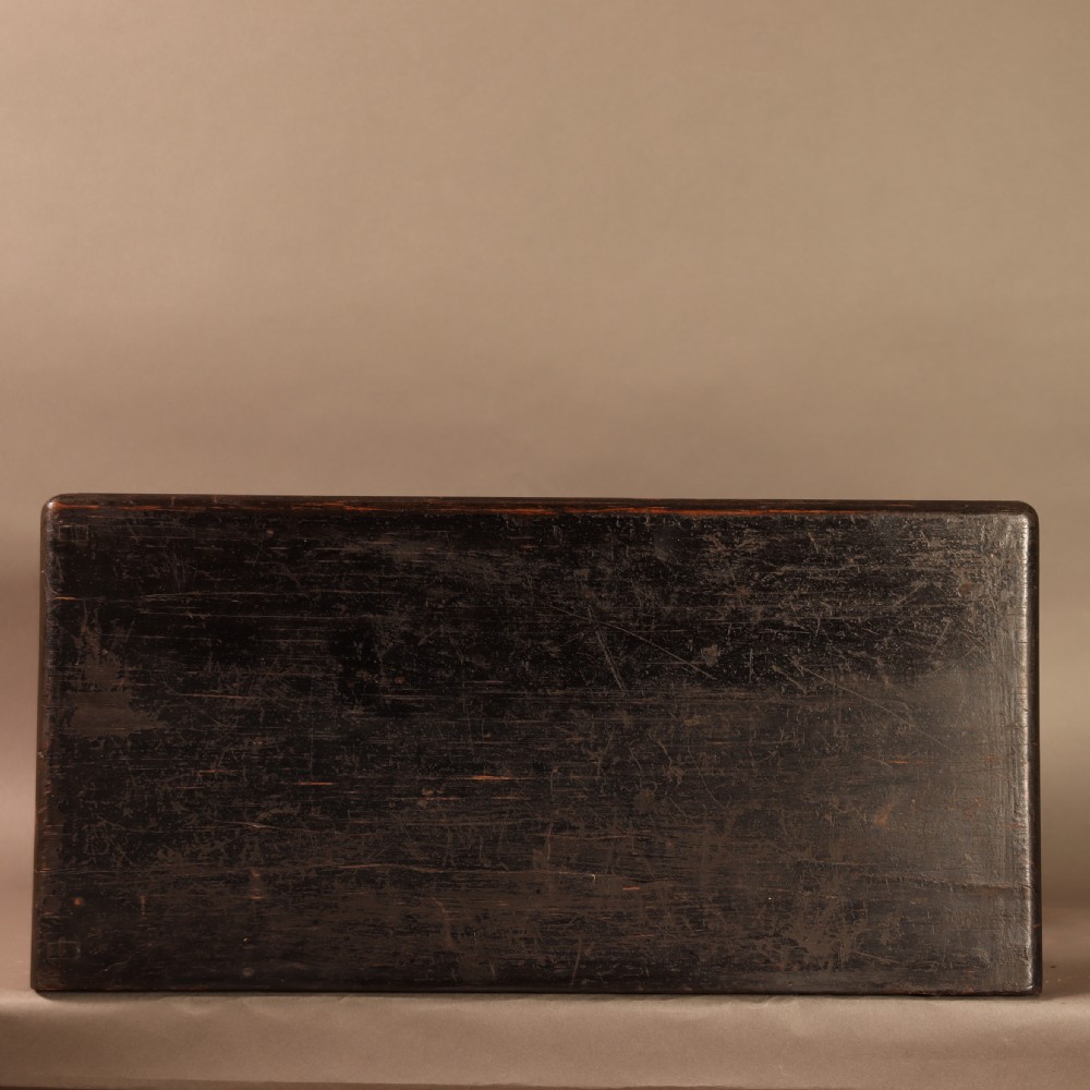 An early 20th-century cased taxidermy pet dog seated on a red fabric cushion against a painted sky background inside a glazed wooden case with gilt trim. View X
