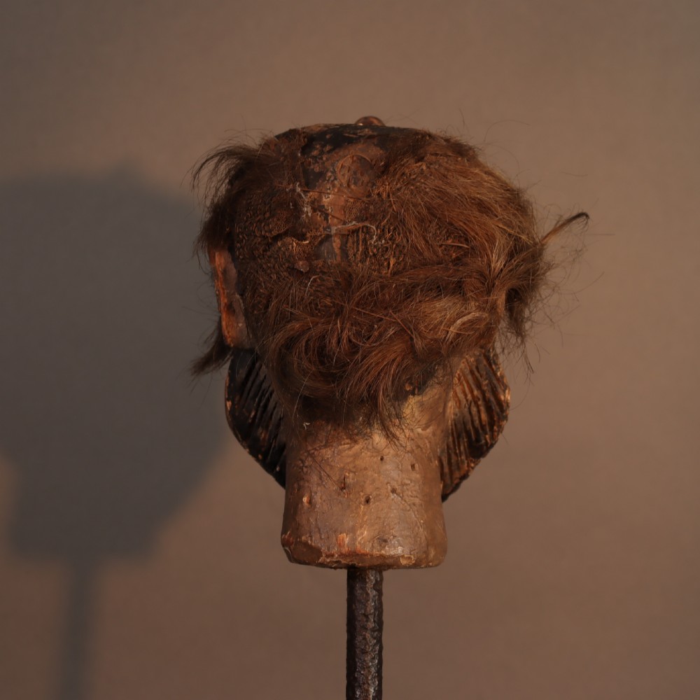 A nineteenth-century carved and polychrome painted wooden puppet head featuring natural hair and a bearded face, displayed on a metal stand. View V
